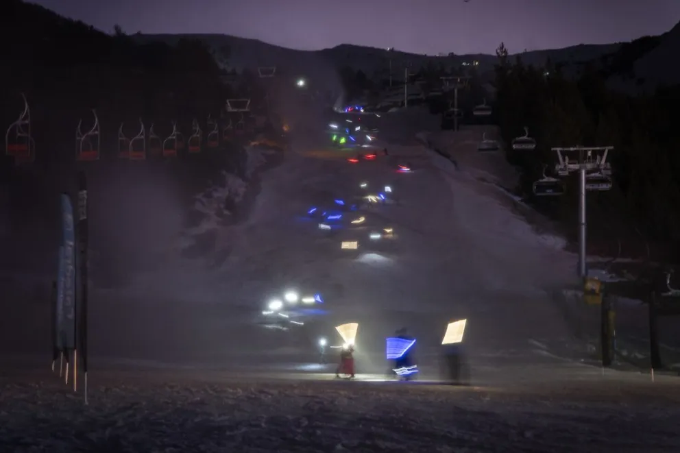 Al anochecer, un surco de colores ilumina la bajada del cerro Catedral emocionando a los espectadores. Foto: Marcelo Martínez.
